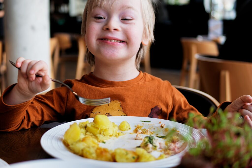 A young boy with Down's syndrome eats lunch in a restaurant.